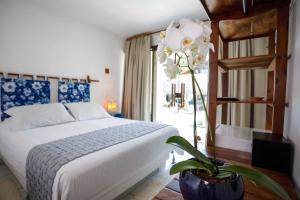 Un dormitorio con una cama y una flor en un jarrón en Pousada Rigatoni, en Arraial d'Ajuda 75 fotos más