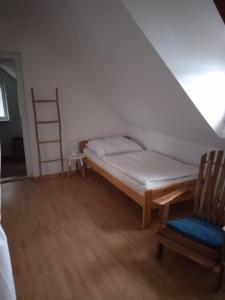 ein Bett in einem Zimmer mit einer Leiter und einem Stuhl in der Unterkunft Dovolenkový dom priamo na brehu in Dunajská Streda