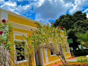 un edificio amarillo con flores delante en O Canto Pousada, en Piranhas