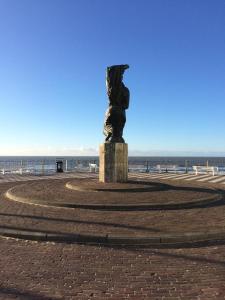 une statue sur la plage avec l'océan en arrière-plan dans l'établissement 't Sand Apartment, à Zandvoort