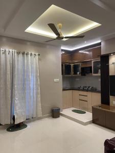 a living room with a ceiling fan and a kitchen at AVVAIRAM SERVICE APARTMENT G8 in Chennai