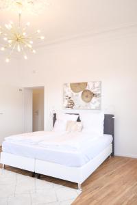 - une chambre blanche avec un lit blanc et un lustre dans l'établissement Honeybee Properties Ferienwohnungen Koblenz, à Coblence