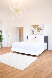 - une chambre blanche avec un lit blanc et un lustre dans l'établissement Honeybee Properties Ferienwohnungen Koblenz, à Coblence