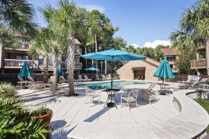 una piscina con sillas y una mesa con sombrilla azul en 21 Moorings, en Hilton Head Island