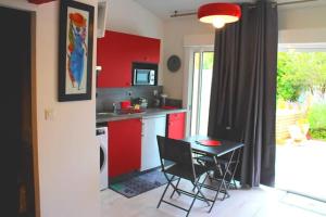 uma cozinha com armários vermelhos, uma mesa e cadeiras em La Cotinière, studio avec cuisine 50 m de la plage em La Cotinière