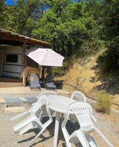 een tafel en stoelen met een paraplu en een trailer bij Caravanes de Provence in Aiglun