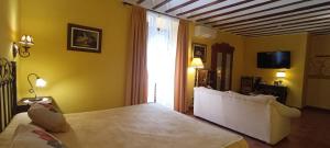 a bedroom with a bed and a tv and a couch at Hotel Rural Posada Los Caballeros in Almagro