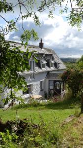 uma casa branca numa colina com relva verde em Higher Trenear Farm B&B em Helston