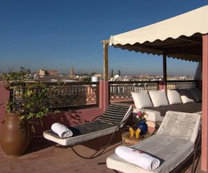 a balcony with two lounge chairs and an umbrella at Riad Imilchil in Marrakesh