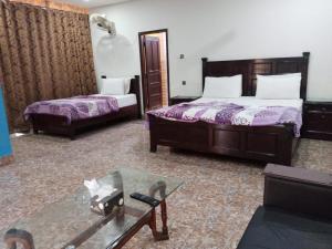 a hotel room with two beds and a glass table at Hotel Sky Inn Clifton in Karachi