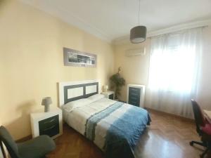 een slaapkamer met een bed, een stoel en een raam bij Apartamento en Retiro in Madrid