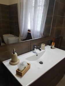 ein Badezimmer mit einem Waschbecken, einem Spiegel und einem WC in der Unterkunft B&B Villa Mirella in Casnate con Bernate