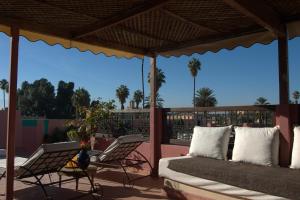 porche con cama y sillas en el patio en Riad Imilchil en Marrakech