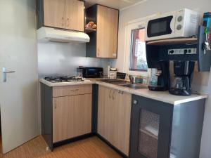 małą kuchnię z kuchenką i kuchenką mikrofalową w obiekcie Mobil Home Les salins de la gardiole w mieście Vic-la-Gardiole