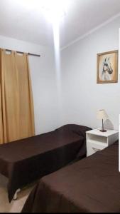 1 dormitorio con 2 camas y mesa con lámpara en Departamento Aquí & Ahora con aire frio calor en Villa Carlos Paz