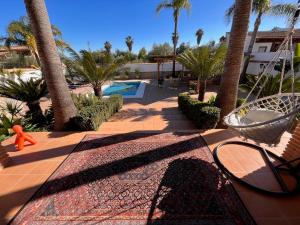 a rug on a patio with palm trees and a pool at Casa Limon, boutique Bed and Breakfast, Andalucia in Alhaurín el Grande