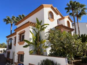 a white house with palm trees in front of it at Casa Limon, boutique Bed and Breakfast, Andalucia in Alhaurín el Grande