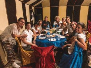 a group of people sitting around a table in a tent at Erg chebbi Dunes Desert Camp in Merzouga