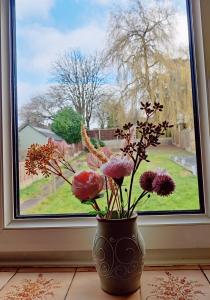 a vase with flowers sitting in front of a window at Sherlock's House-Melbourne 4 rooms 8 beds Free Private parking Free super Wifi Working facility 42" smart TV in Burton upon Trent