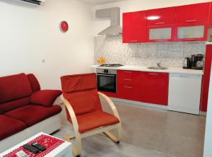 cocina con armarios rojos, silla roja y sofá en Apartman Sanja en Pula