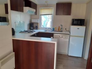 Una cocina con un refrigerador blanco y un fregadero. en MOBILHOME agréable sans draps ni serviettes, en Port-la-Nouvelle