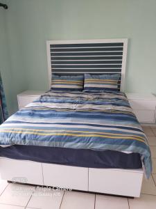 a bed with a blue and yellow striped comforter at Mia Haven 2 in Scottburgh