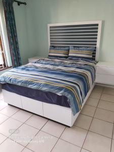 a bed with a blue and yellow striped comforter at Mia Haven 2 in Scottburgh