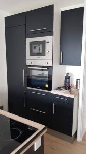 uma cozinha com armários pretos e um micro-ondas em Le Viva em Saint-Étienne