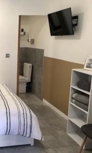 1 dormitorio con aseo y TV en la pared en Studette de 17m2 avec parking privé gratuit Climatisation et petite cuisine, en Menton