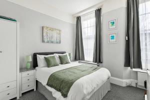 a white bedroom with a large bed and windows at South view in Torquay