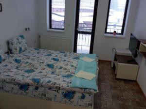 1 dormitorio con 1 cama, TV y 2 ventanas en Стаи за гости ''Живел'' en Oreshak