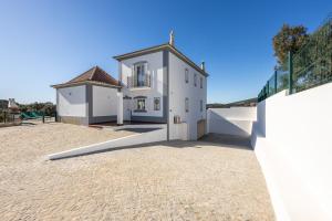 a large white house with a fence in front of it at Casa do Limoeiro in Tavira