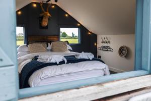 a bedroom with a large bed and a mirror at The Treehouse at Humblebee Hall in Worcester