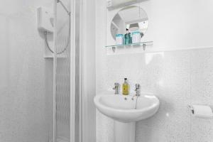 a white bathroom with a sink and a mirror at South view in Torquay