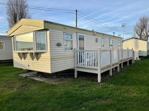 a yellow house with a porch and a deck at Lyntons 3 bedroom caravan pets stay free in Heacham