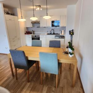 uma cozinha com uma mesa de madeira e cadeiras azuis em Lovely Apartment for 4 on the Danube River - Private Parking em Viena