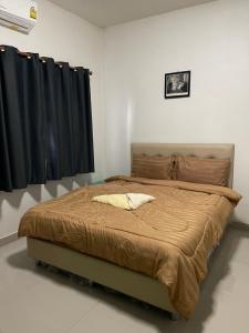 a bed in a bedroom with a black curtain at ควีนเพลส สระบุรี Queenplace Saraburi in Sara Buri