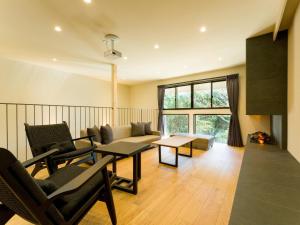 a living room with a couch and chairs and a fireplace at Rakuten STAY VILLA Kamogawa Building B with Terrace and sauna Capacity of 12 persons in Kamogawa