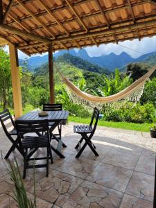 a patio with a table and chairs and a hammock at Lumiar - Casa do Sol in Nova Friburgo