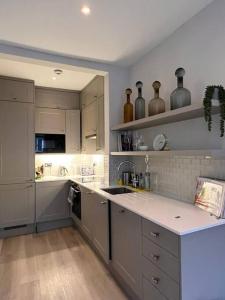 倫敦的住宿－One bedroom flat in Chelsea，厨房配有灰色橱柜和白色台面