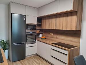 a kitchen with a stainless steel refrigerator and wooden cabinets at Nový apartman Eva in Jičín