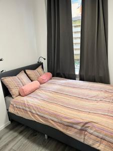 Un dormitorio con una cama con almohadas rosas y una ventana en ‘T Singeltje en Leiden