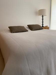 a white bed with two pillows and a lamp at Chez Ocean Plaza in Figueira da Foz