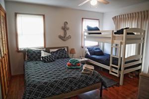 ein Schlafzimmer mit einem Bett und einem Etagenbett in der Unterkunft Lake Front Modern Beach House-Hatteras Island in Avon