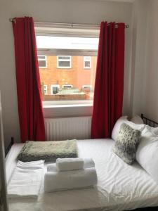 a bedroom with a bed with red curtains and a window at Chester le Street Amethyst 3 Bedroom House in Chester-le-Street