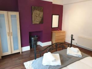 a bedroom with purple walls and a bed with two towels at South Shield's Hidden Gem Garnet 3 Bedroom Apartme in South Shields