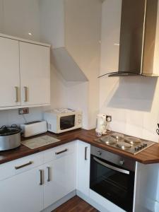 a kitchen with white cabinets and a stove top oven at South Shield's Hidden Gem Garnet 3 Bedroom Apartme in South Shields