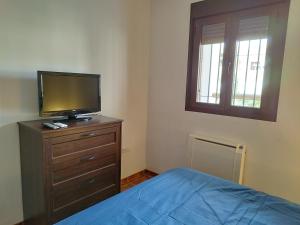 Dormitorio con cama y tocador con TV en Los Olivos de Fondon, en Fondón