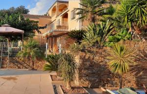a house with a stone wall and palm trees at Villa U Tramontu in Granace