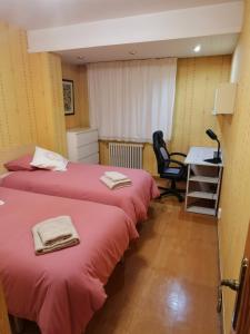 two beds in a room with a desk and a chair at Cómoda vivienda en Huesca in Huesca